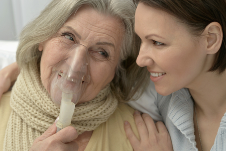 Senior ill woman with caring daughter at homeの写真素材