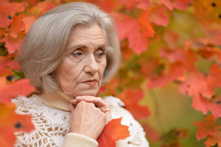 Portrait of a sad elderly woman in autumn parkの写真素材