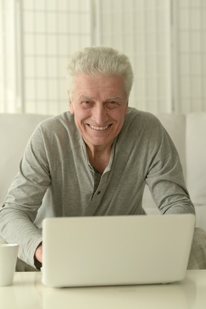 Portrait of a happy senior man using laptop