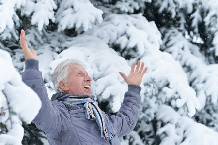 Portrait of exited senior man in a snow-covered winter parkの写真素材