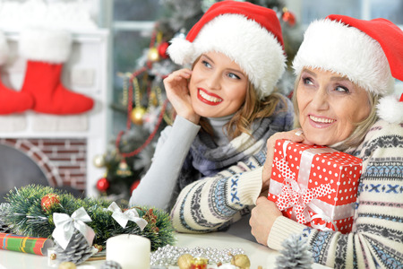 Portrait of smiling senior and young women in Santa hats looking at the distanceの写真素材
