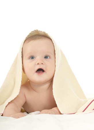Adorable baby boy lying under blanket on a white backgroundの写真素材