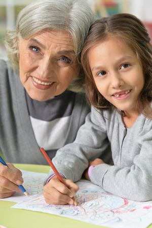 Portrait of grandmother and granddaughter drawing togetherの写真素材