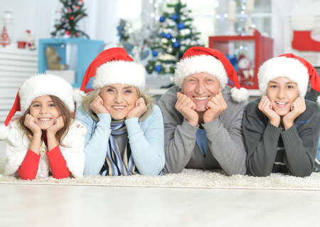 Portrait of happy family in Santa hats lying on the floorの写真素材