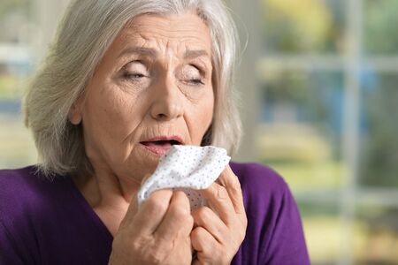 Portrait of senior wooman feels sick, holds  handkerchiefの写真素材