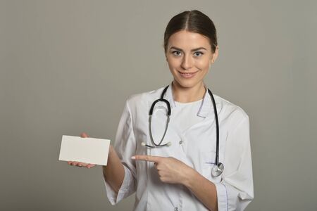 Female doctor with white list, standing on grey backgroundの写真素材