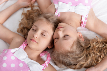Portrait of two sisters twins sleeping togetherの写真素材