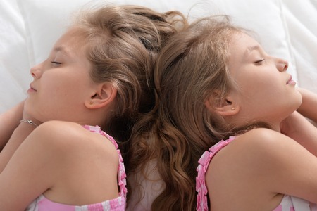two sisters twins sleepingの写真素材