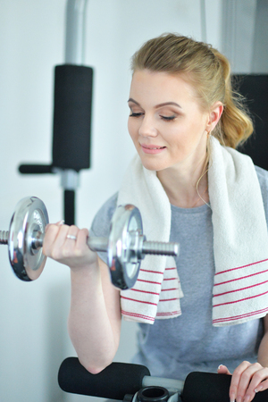 Young woman in a gym with a dumbbellの写真素材