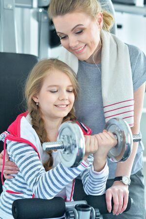 Young woman with her teenage daughter in a gym with dumbbellsの写真素材