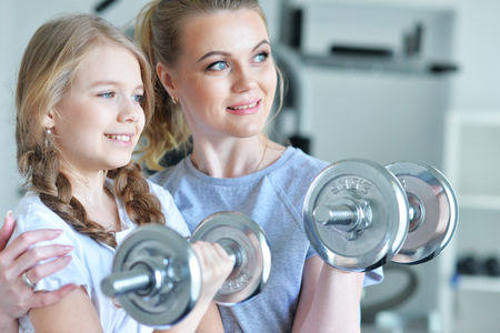 Young woman with her teenage daughter in a gym with dumbbellsの写真素材