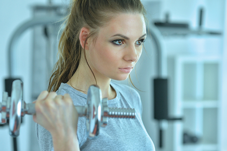 Young woman in a gym with a dumbbellの写真素材