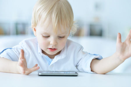 Boy is playing with a mobile phoneの写真素材