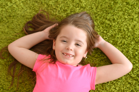 Smiling girl lying on the carpetの写真素材