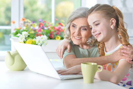 Girl with grandmother using laptopの写真素材
