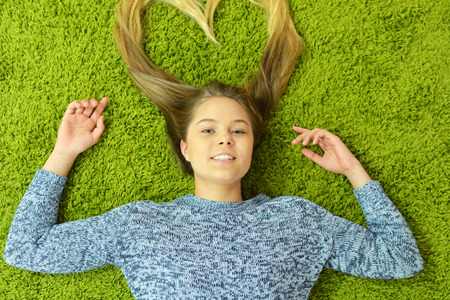Teen girl lies on the carpetの写真素材