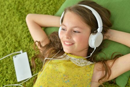 Cute little girl with smartphone and headphones