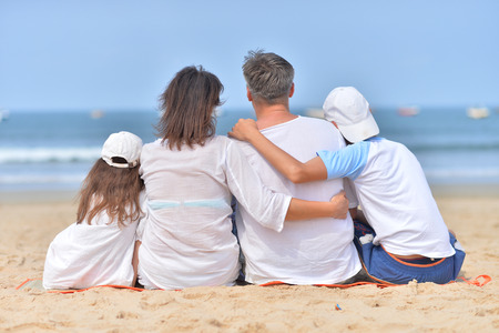 family sitting on sandy beachの写真素材