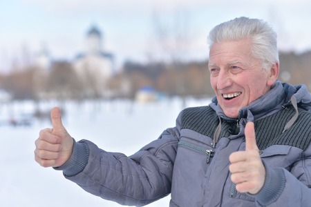 senior man standing outdoors and showing thumbs upの写真素材