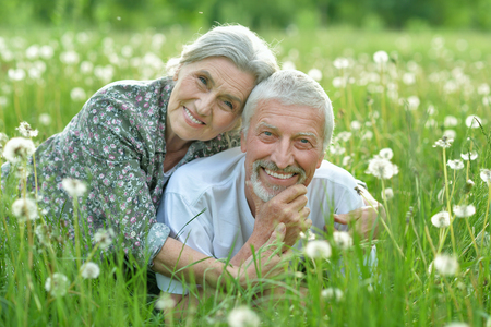 happy senior couple lying on green meadowの写真素材