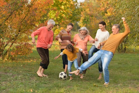 Big happy family playing football in autumn parkの写真素材