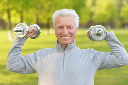 Portrait of elderly man exercising with dumbbellsの写真素材