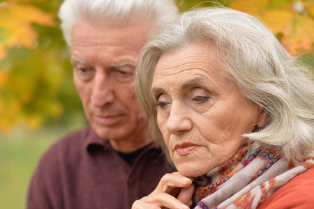 Close up portrait of sad senior couple in autumn parkの写真素材