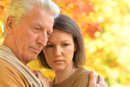 Portrait of sad woman and senior man huggingの写真素材