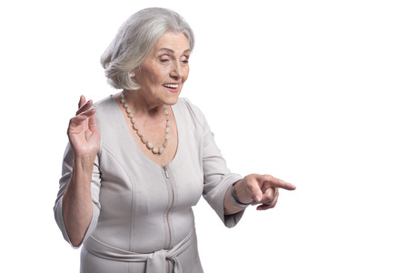 Beautiful senior woman pointing to the right on white background