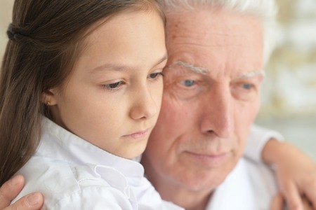 Close up portrait of sad grandfather and granddaughterの写真素材
