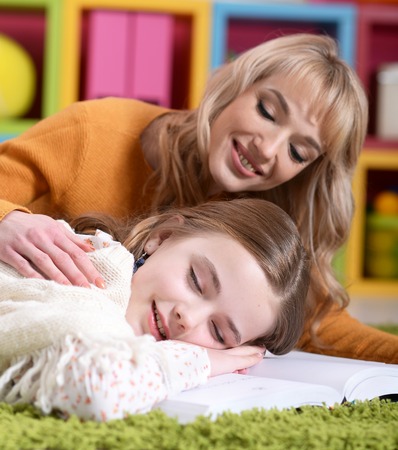Portrait of beautiful mother waking up her little daughterの写真素材