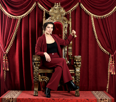 Portrait of beautiful young queen sitting on chair