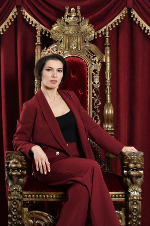 Portrait of beautiful young queen sitting on chair