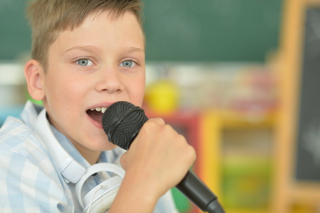 Portrait of boy singing karaoke at homeの写真素材