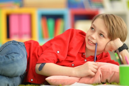 Portrait of cute little boy drawing at home