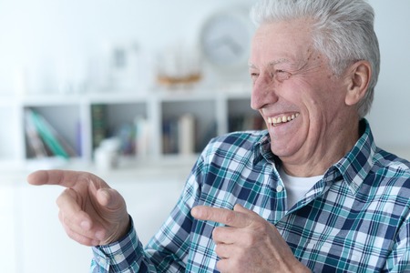 Portrait of senior man in checkered shirt pointing to the rightの写真素材