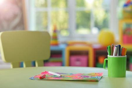 Cup with pencils and colorful drawing on a tableの写真素材