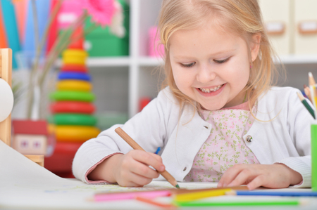 Beautiful little girl drawing at her roomの写真素材