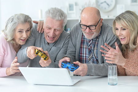 two senior couples using laptop at home