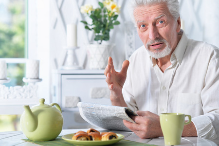 Portrait of emotional senior man reading newspaperの写真素材