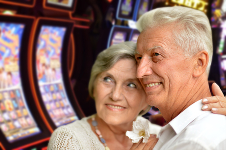 Portrait of happy senior couple posing on blurred casino hall backgroundの写真素材