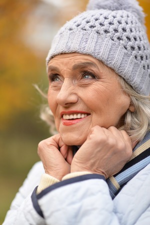 Portrait of senior beautiful woman in autumnal parkの写真素材