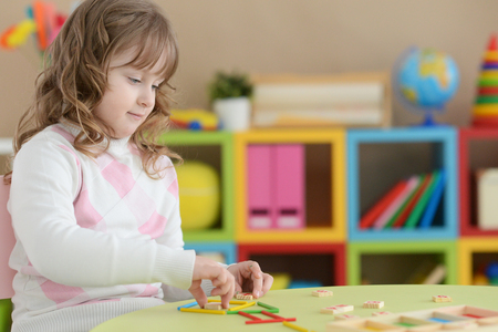 Portrait of cute curly girl learning to count with sticks at roomの写真素材