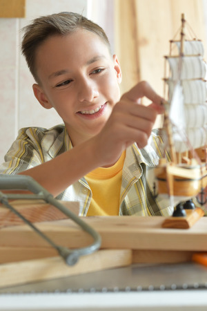 boy with model of ship and handsawの写真素材