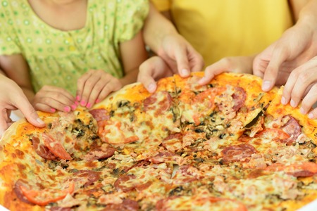family together eating round pizzaの写真素材