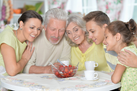Portrait of big happy family eating fresh strawberries at kitchenの写真素材