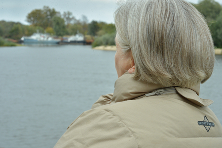Elderly woman  standing  near lakeの写真素材