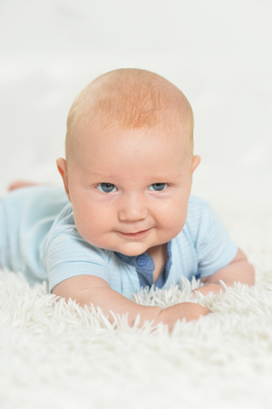 Portrait of beautiful baby boy on bedの写真素材