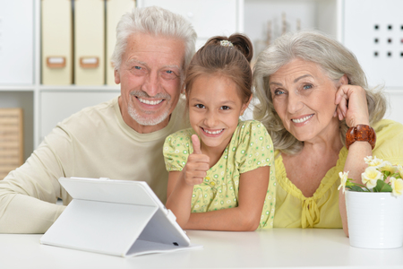 Grandparents with her granddaughter using laptop at homeの写真素材