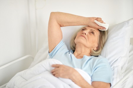 Portrait of a sick senior woman in hospitalの写真素材